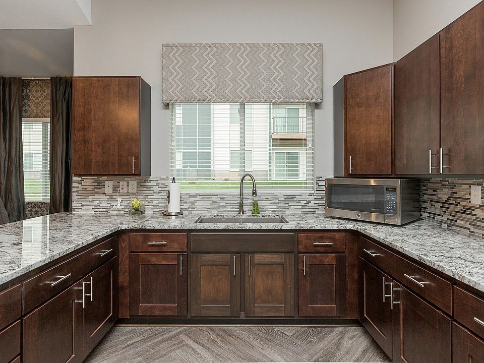 Cook and entertain in style with granite countertops, rich cherry cabinets, a bright window view, and decorative backsplash.