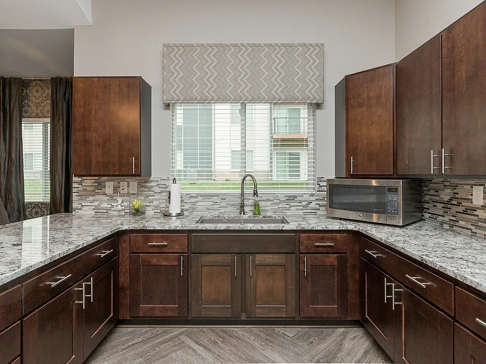 Cook and entertain in style with granite countertops, rich cherry cabinets, a bright window view, and decorative backsplash.