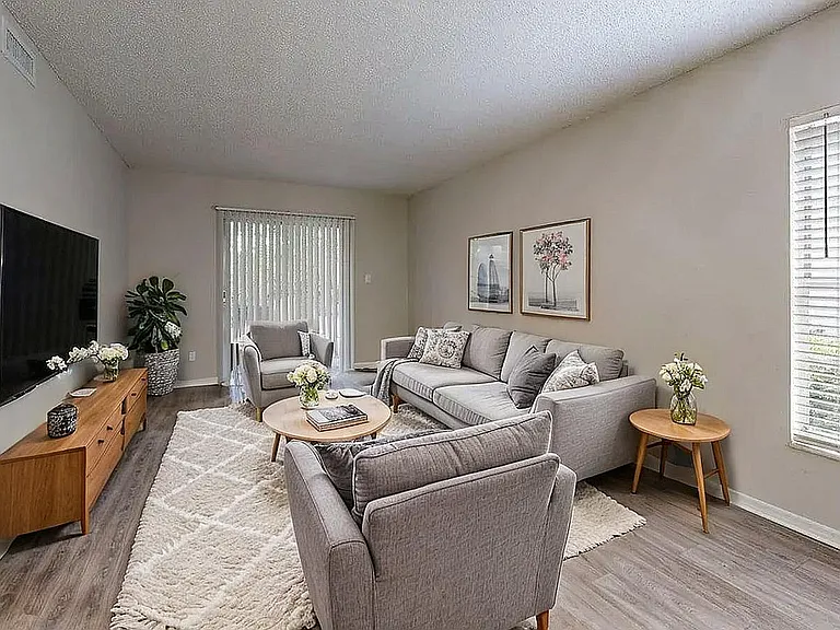Inviting living room with chic gray sofas, modern wall art, and a sleek TV setup, bathed in natural light from large windows.
