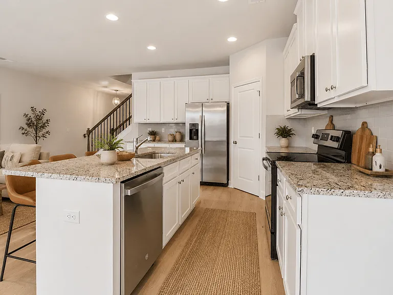Spacious kitchen with an island, ample storage, stainless steel appliances and view into the living room.