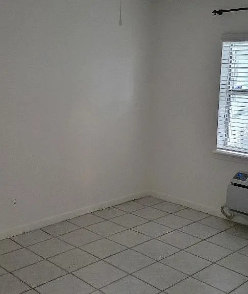 Tiled bedroom with one window and ceiling fan.