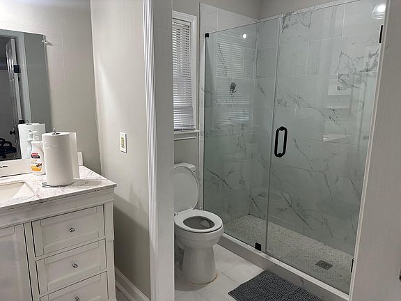 Updated bathroom with a glass-enclosed walk-in shower, tiled surround, and a spacious vanity with ample storage.