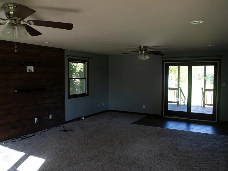 Living room with walk-out deck access and entertainment wall.