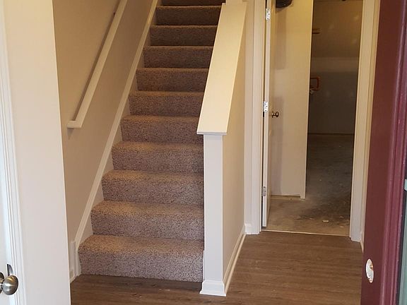 Foyer; stairs to living area; door to utility room/storage area; door to garage (unseen) is on right wall.