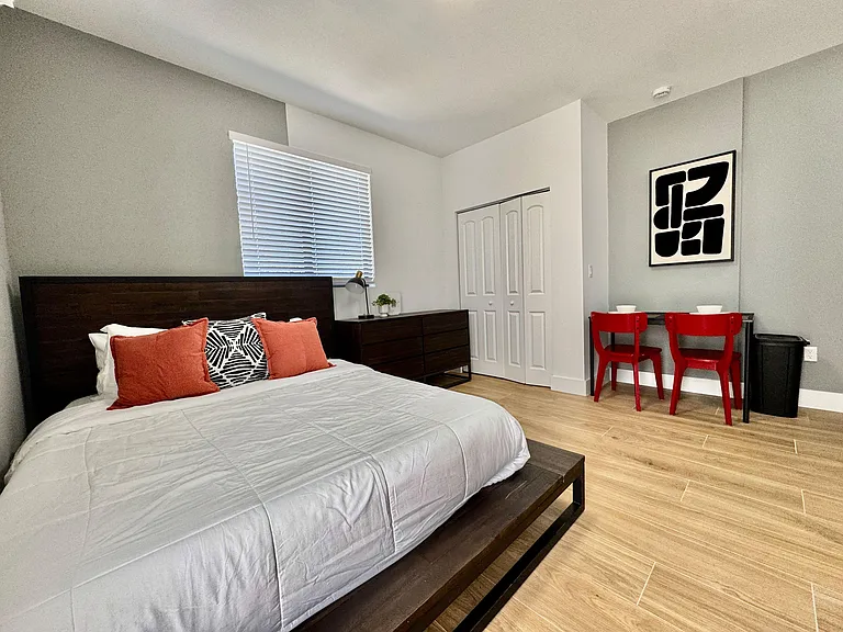 Furnished bedroom with a comfortable bed, dresser storage, and a built-in desk area for work or study.