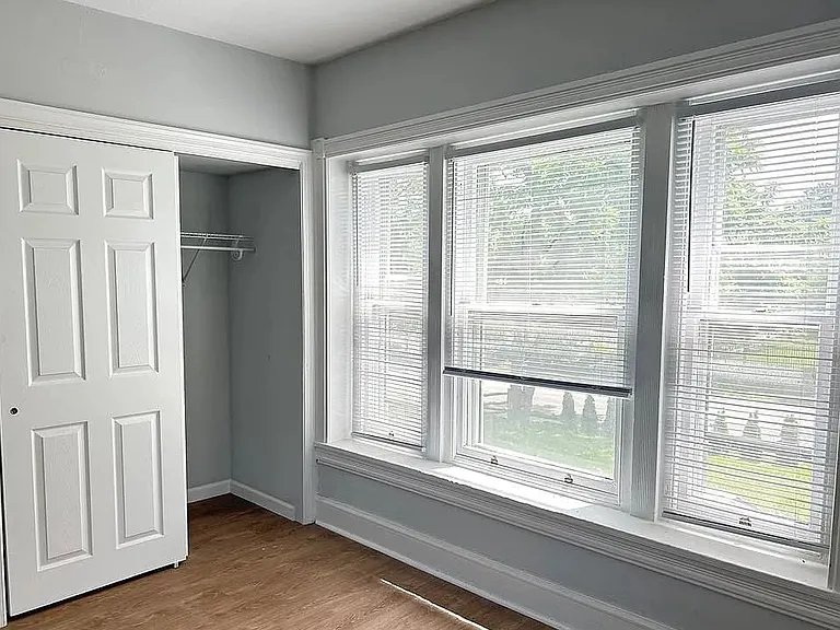 Bright primary bedroom featuring a large picture window, generous closet space, and updated flooring. Freshly painted with abundant natural light, creating a comfortable and relaxing retreat.