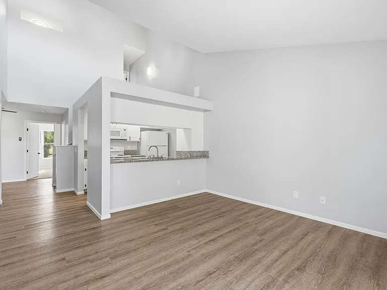 A spacious kitchen and living room with hardwood floors and white walls.