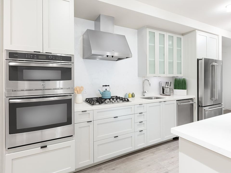 Kitchen with white cabinetry, quartz stone countertops, ceramic tile backsplash and stainless steel appliances