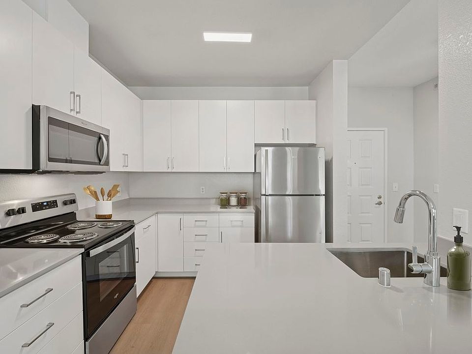 Renovated Package I kitchen with white cabinetry, grey quartz countertops, stainless steel appliances, and hard surface flooring