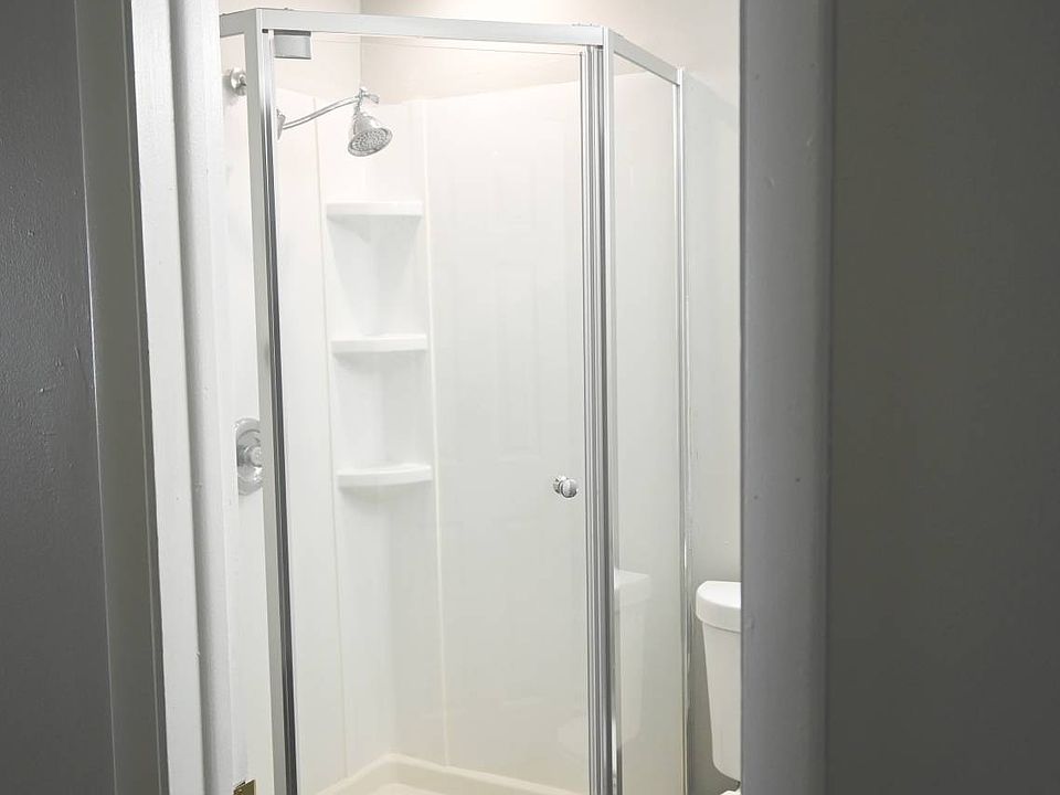 Walk-in shower with glass doors in a unit at Benson Crest Apartments.