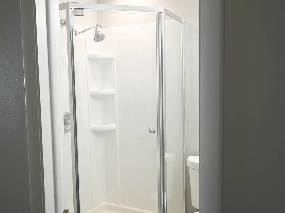Walk-in shower with glass doors in a unit at Benson Crest Apartments.