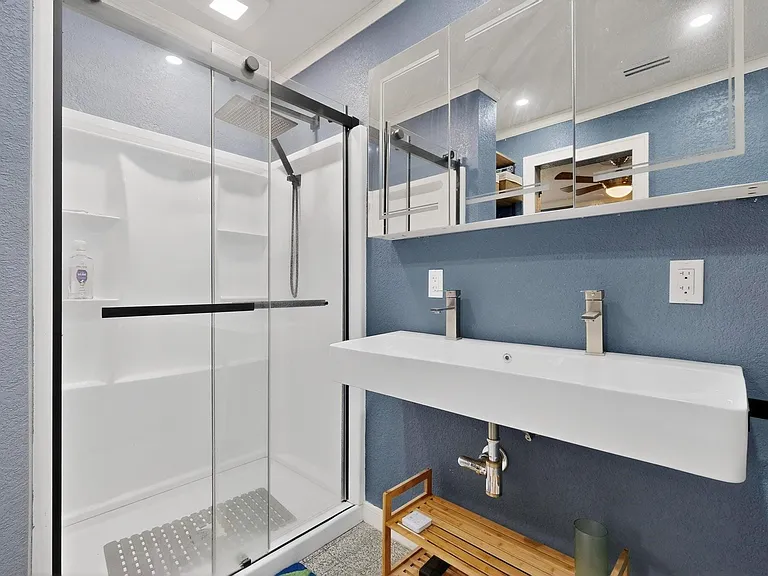 The primary bathroom with a dual sink and separate shower, featuring blue walls and white fixtures, creating a fresh and clean atmosphere.