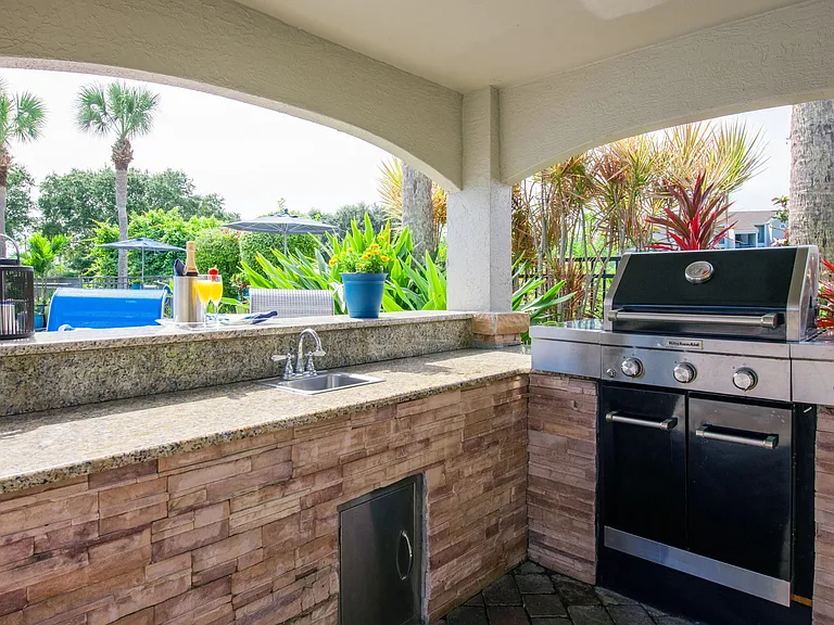Savor the good life mastering the grill in our shaded outdoor kitchen, complete with a sink, ample counter space, and everything you need to whip up a poolside culinary masterpiece.