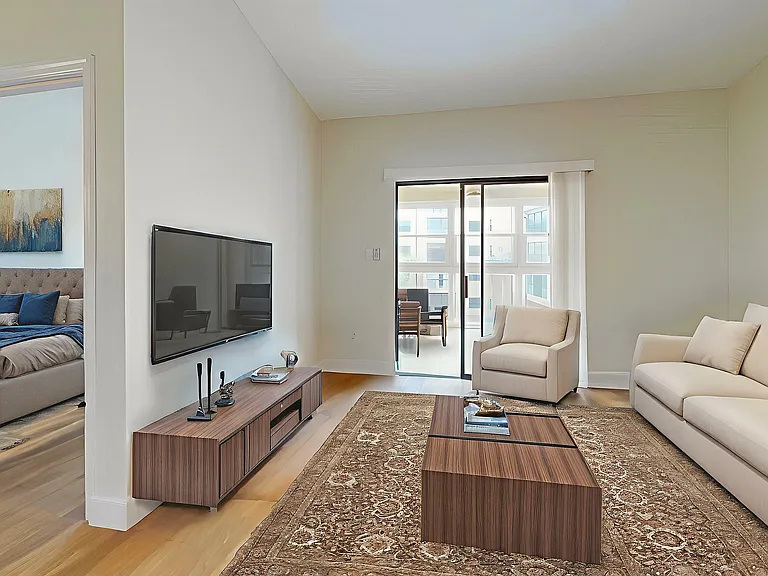 Bright and modern living room with elegant decor, featuring a cozy beige sofa, stylish wooden furniture, and a view into a welcoming bedroom.