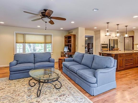 65" Smart Flat screen hangs above the granite faced wood fireplace. Flanked by custom Amish built in cabinets. 1/2 bath door can be seen, with garage access just to the left. Wash room across from the 1/2 bath.