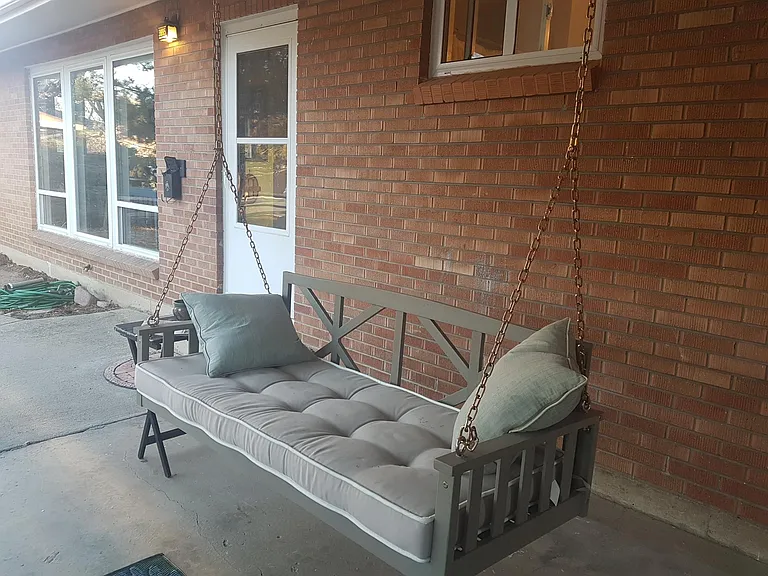 Porch swing under overhang faces the garden and street!