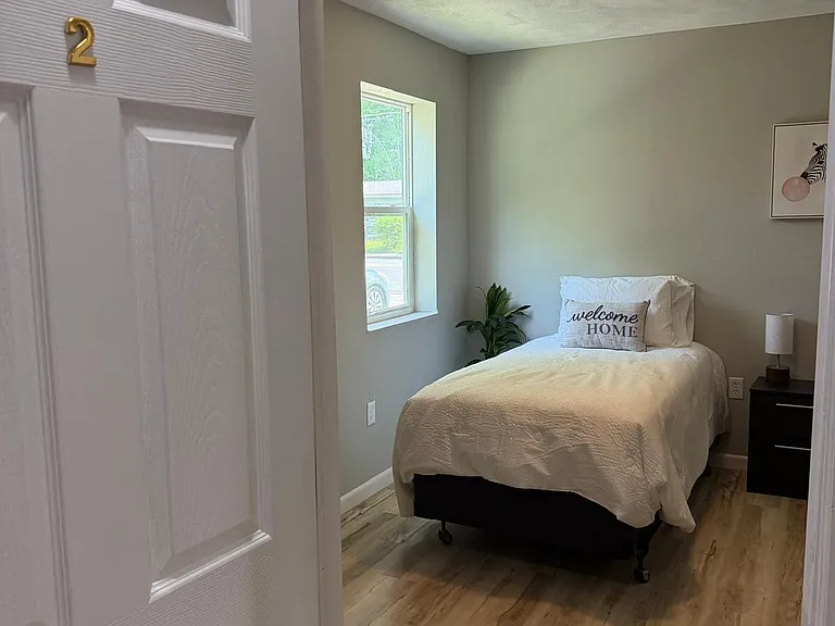 Private bedroom with wood-style flooring, a window for natural light, and space for a twin bed and nightstand.