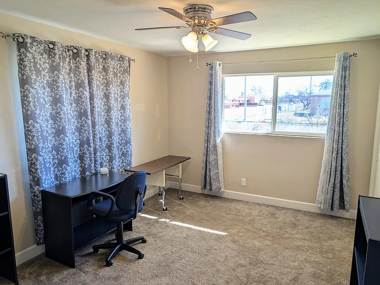 Bedroom 4 setup as office with 2 desks, chair, bookshelves, hi-speed wifi extender, ceiling fan and cot