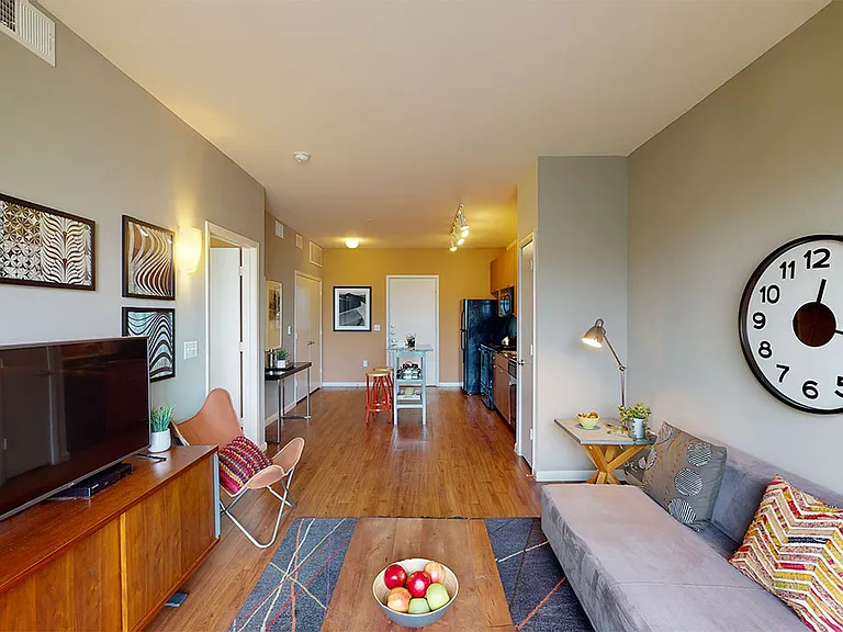Apartment kitchen, dining and living room with wood-style flooring.