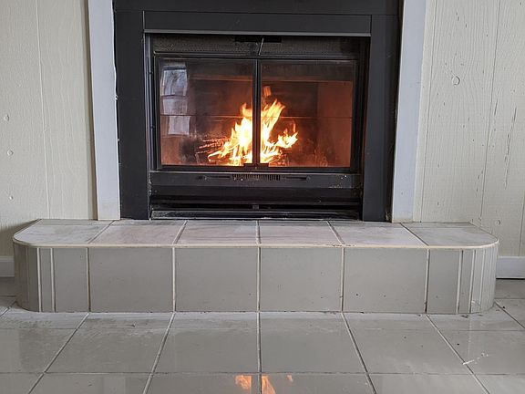 Large dining, living room or office with wood heat exchanging fireplace and white marbled tile floor