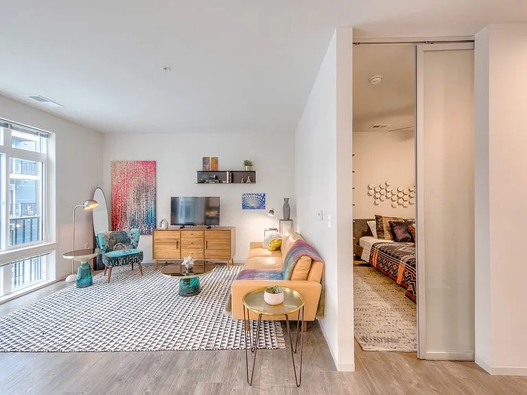 Living area and bedroom with hard surface flooring and sliding barn door