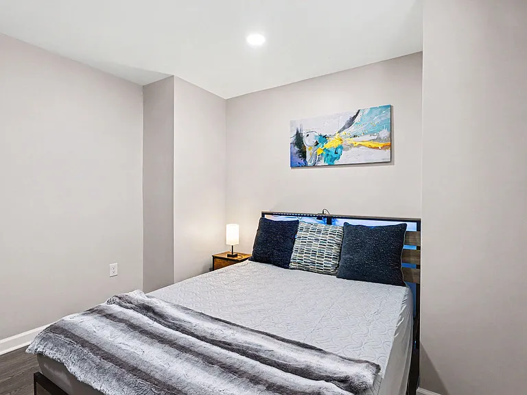 Furnished bedroom with a full bed, nightstand lighting, and neutral walls for an easy-to-arrange layout.
