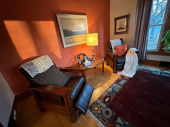 living room with leather couches and chairs, drapes, carpet and hardwood floors.