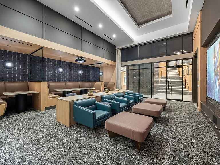Modern communal lounge featuring plush seating, stylish decor, and a large projection screen, perfect for social gatherings.