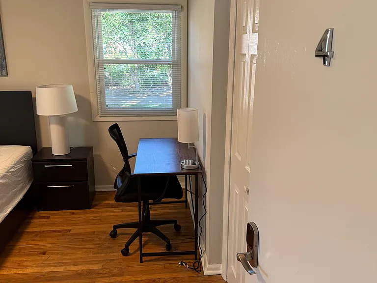 Private bedroom with hardwood floors, a window with blinds, and a dedicated desk area plus closet storage.