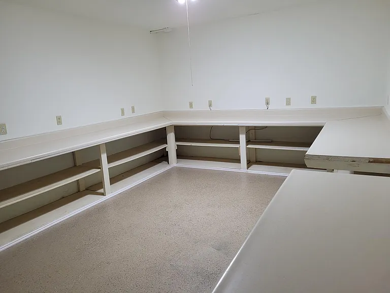 Large storage area in basement with a lot of shelving, sink and hook-up for washer/dryer