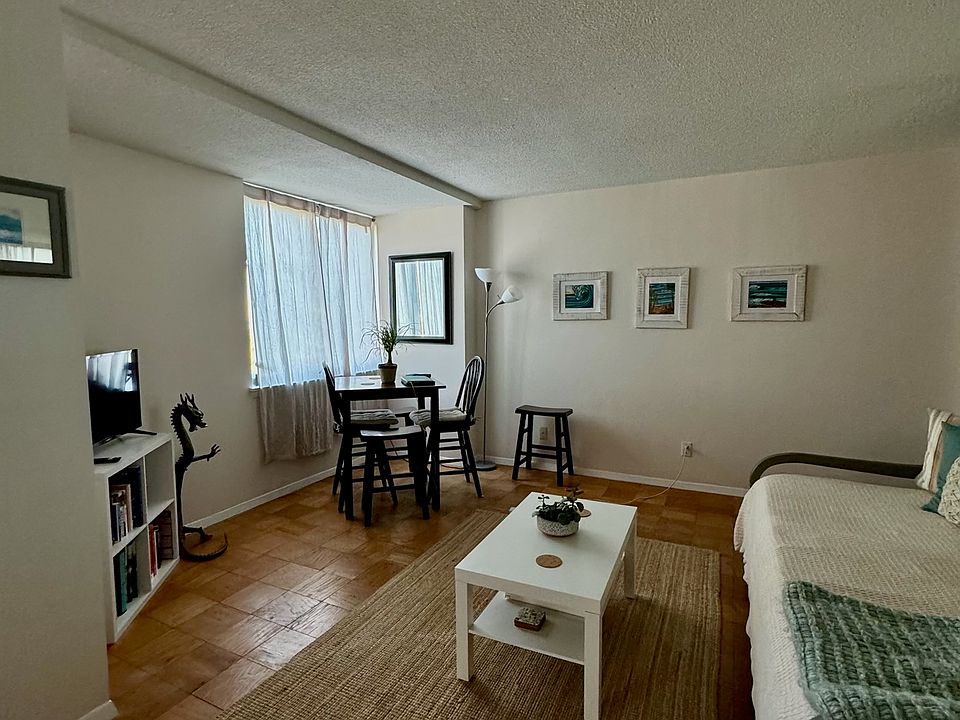 Living room area with Large window lending to DC views ;mirror paneled wall separates kitchen with new appliances.