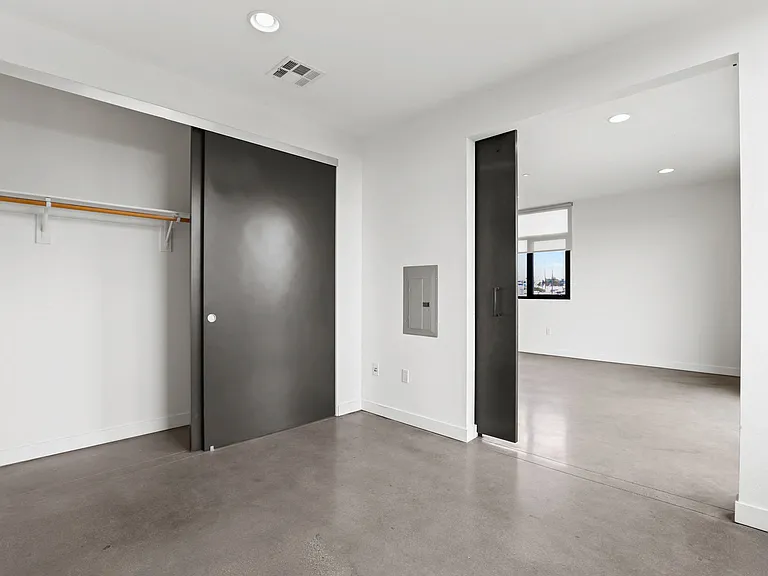 Bedroom withSliding Door, Large-Size Closet, and Concrete Flooring