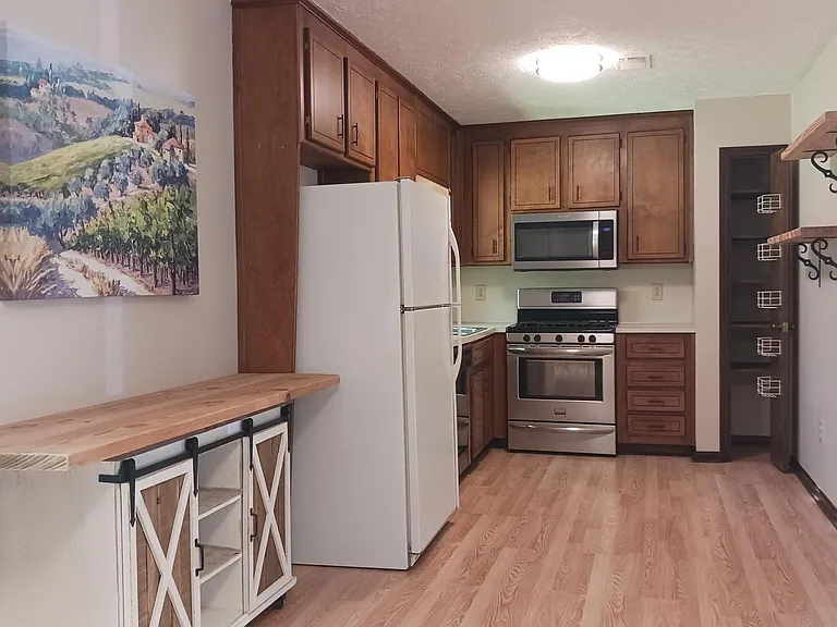 Open kitchen to dining and living room with custom shelving and pantry.