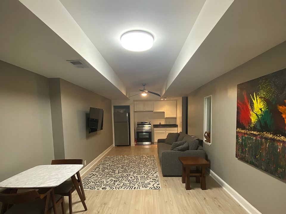 An open concept living room and full kitchen features a cafe table, 55 inch smart TV and sleeper sofa.