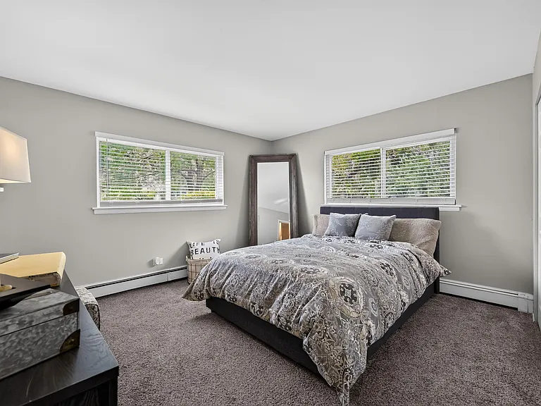 Rest easy in a comfortable bedroom featuring a nightstand and natural light at Renaissance at Carol Stream in Carol Stream, IL.