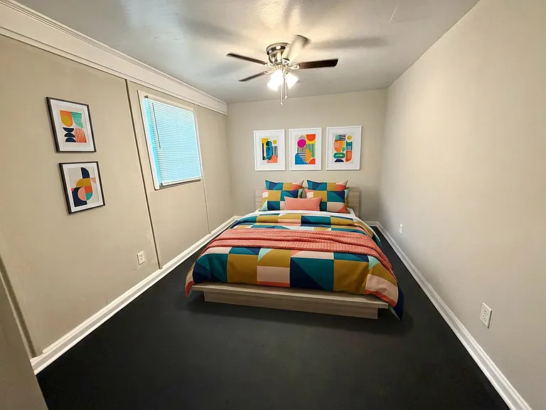 Furnished bedroom with a full bed, ceiling fan, and a window with blinds, offering a simple layout for easy furniture fit.