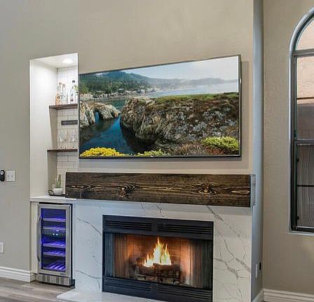 Left of the fireplace is a Custom bar area with wine fridge, wood shelving and white subway tile. 65" LG SmartTV included in rent!