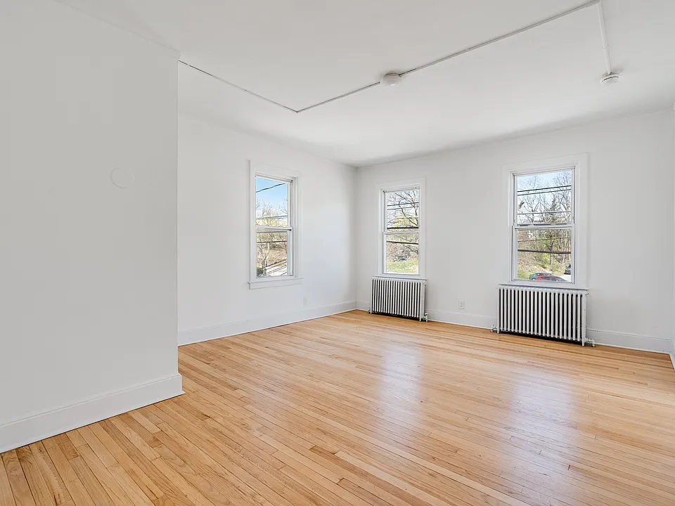 Large living room featuring arched walkways, and light hardwood flooring