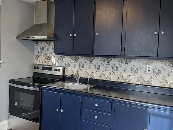Kitchen equipped with new stove and vent hood.