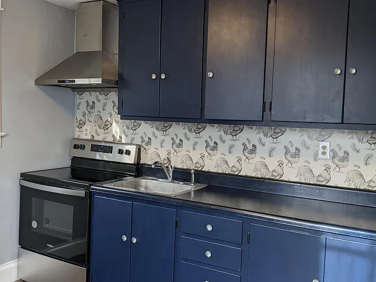 Kitchen equipped with new stove and vent hood.