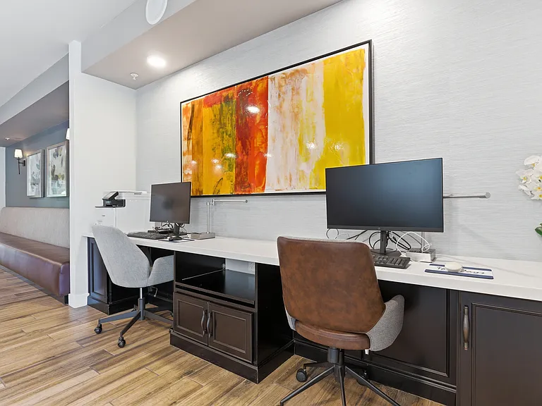 Dedicated business center offering a quiet workspace with multiple computers, monitors, and a printer.