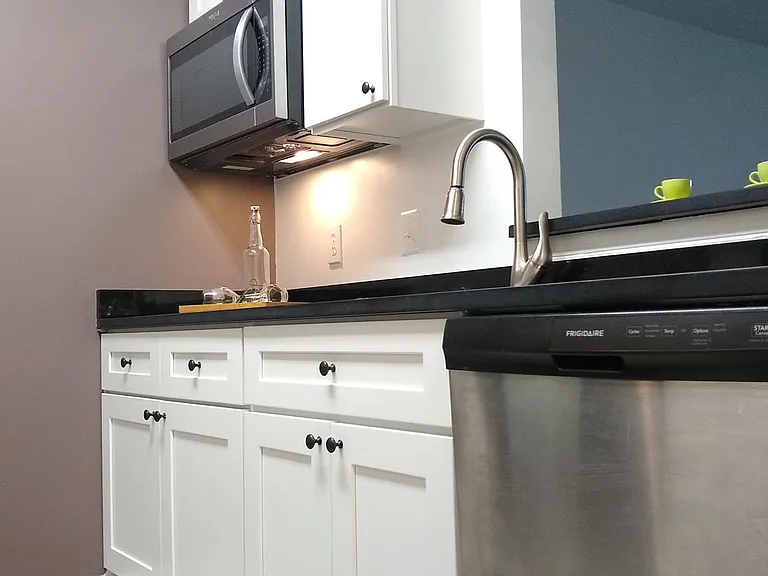 Kitchen with brand new cabinets, countertop, faucet, sink, and new dishwasher and microwave oven.