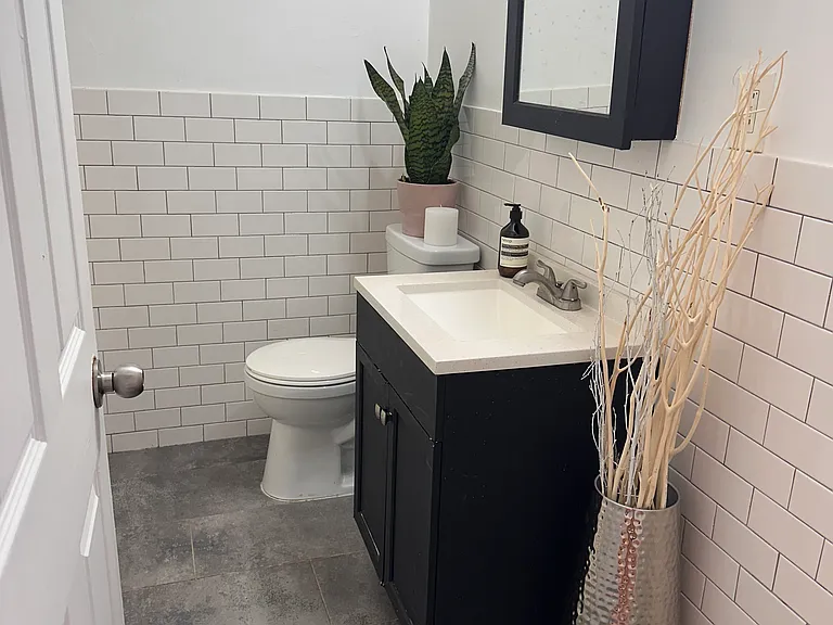 Clean bathroom featuring white subway tile walls, tiled floors.