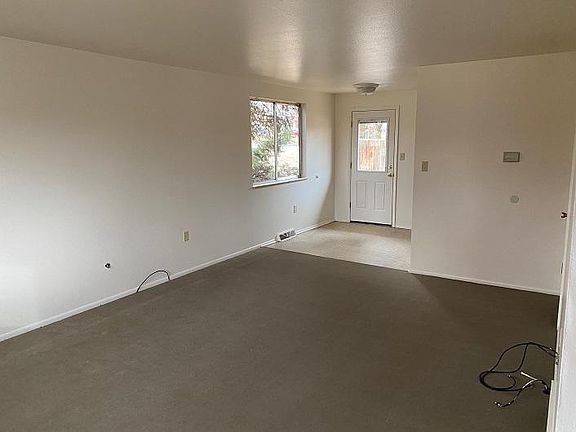 Across living room towards back door and dining/ kitchen/half bath with new carpet