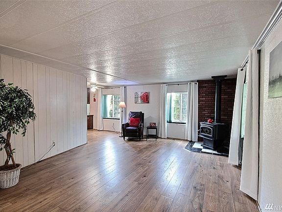 A spacious living room boasting a nice corner woodstove.  If you lose power hear this Winter, no problem you'll be warm! Also lots of windows for added light!