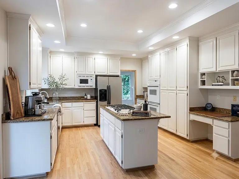 Spacious gourmet kitchen with double ovens, cooktop island, and hardwood floors (computer staged)