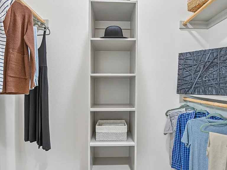 Markethaus 3700 A closet with clothes hanging and shelves with storage boxes.