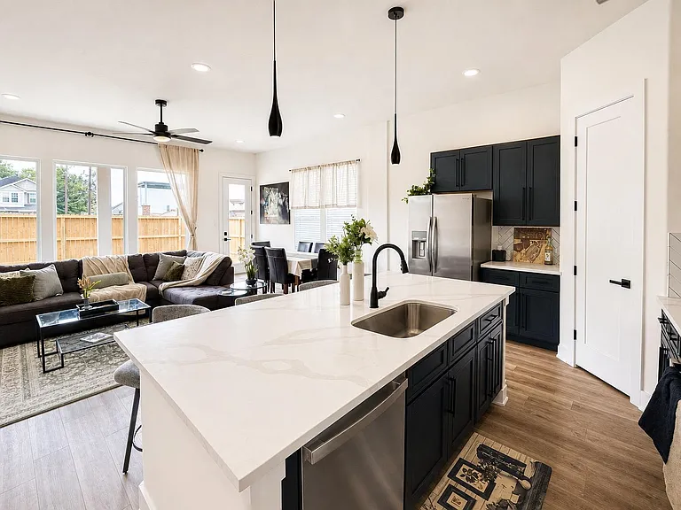 Open-concept kitchen with a large island, stainless appliances, and bar seating, flowing into dining and living areas.