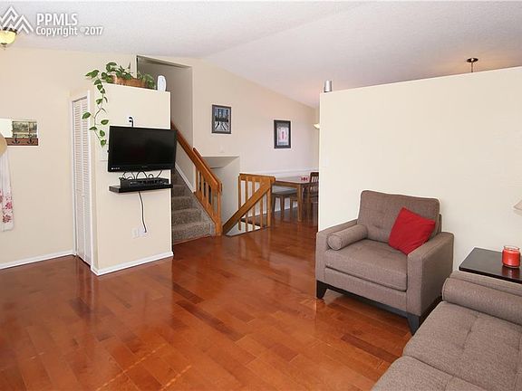 Entry with closet and living room with hardwood floors and vaulted ceilings.