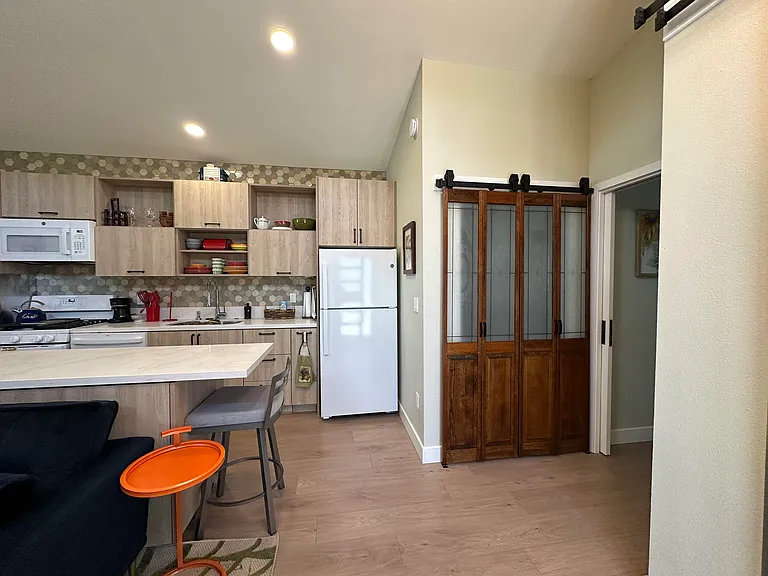 View of kitchen from the front door. Dark wood and glass closet doors have full-sized washer and dryer behind them